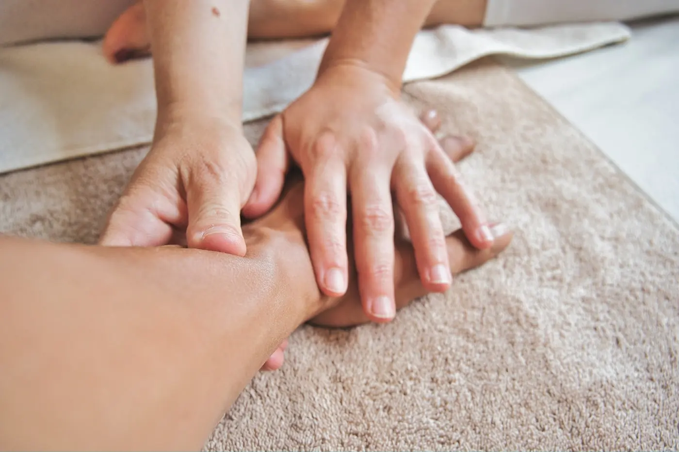 Hände einer Masseurin auf dem Rücken einer liegenden Person