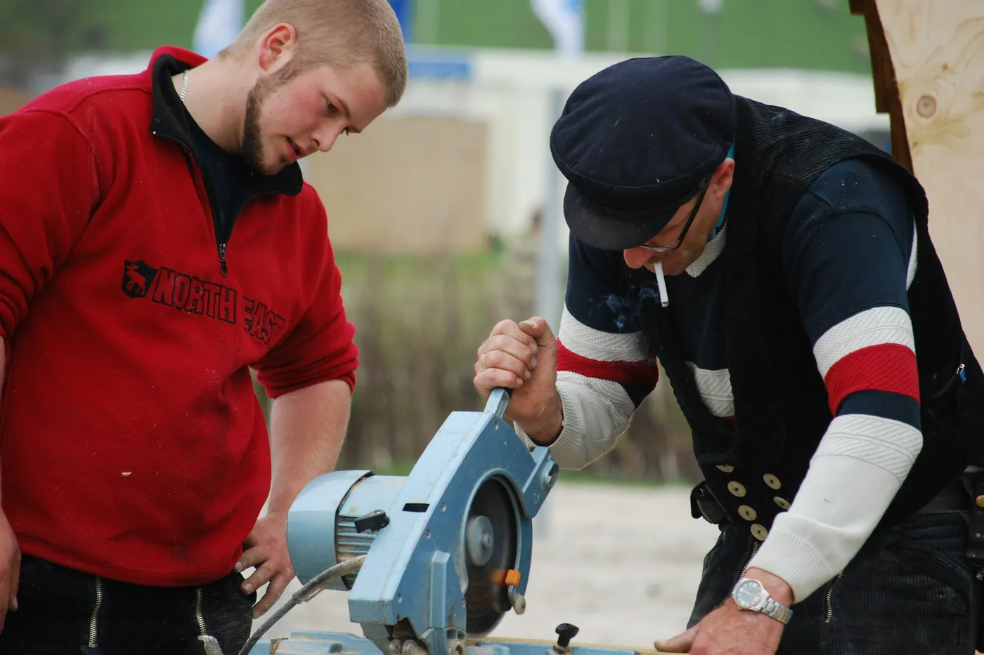 Zwei Personen arbeiten gemeinsam an einer Kappsäge im Freien