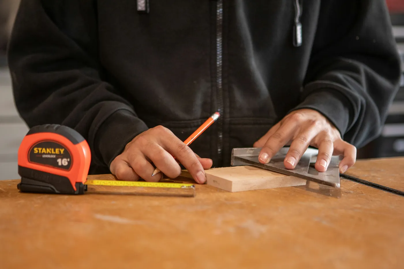 Hände messen ein Brett mit Winkel und Bleistift an
