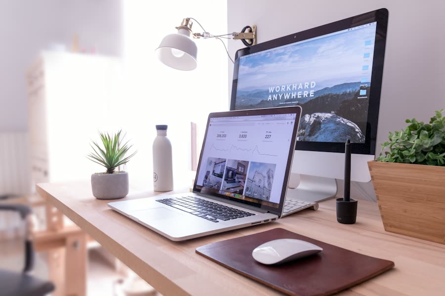 Arbeitsplatz mit iMac und MacBook, beide zeigen eine Website, auf einem Holztisch