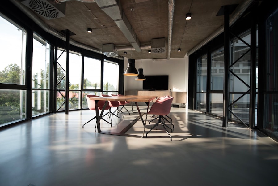 Industrielles Besprechungszimmer mit Holztisch, rosa Stühlen und grosser Fensterfront
