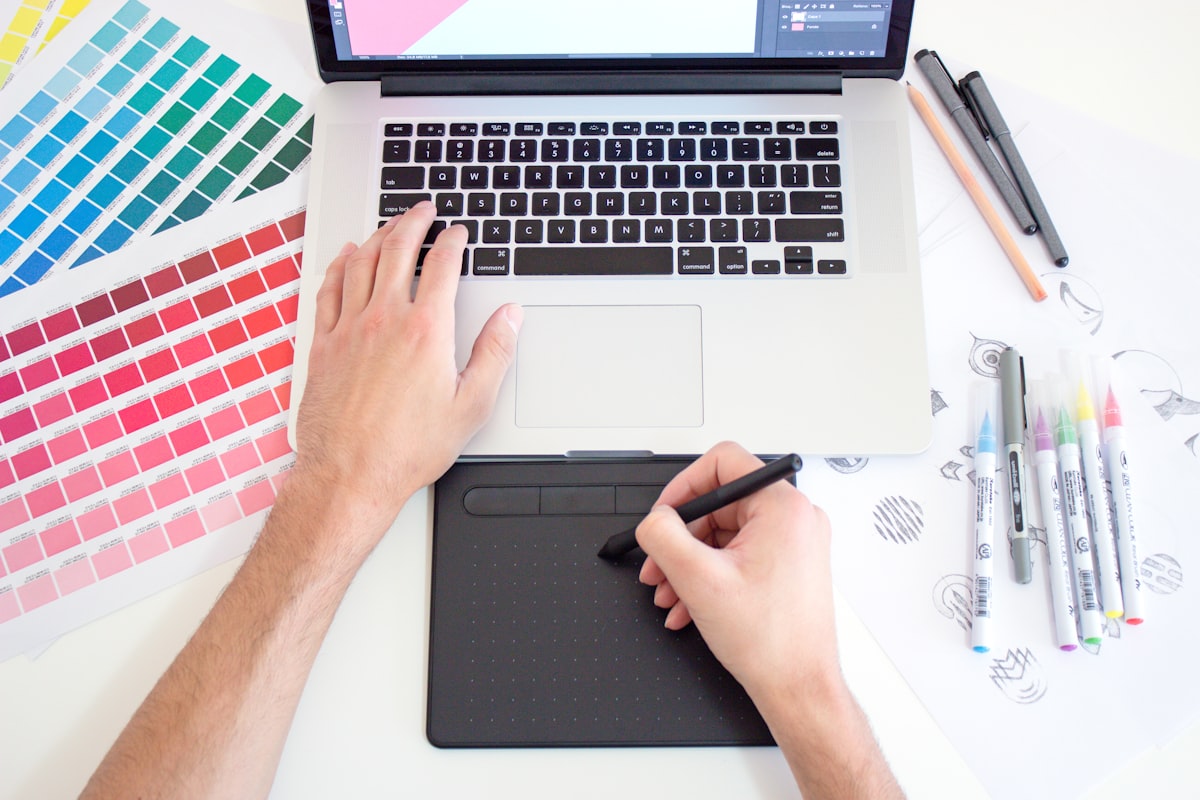 Grafiker arbeitet mit Stift und Grafiktablett am Laptop
