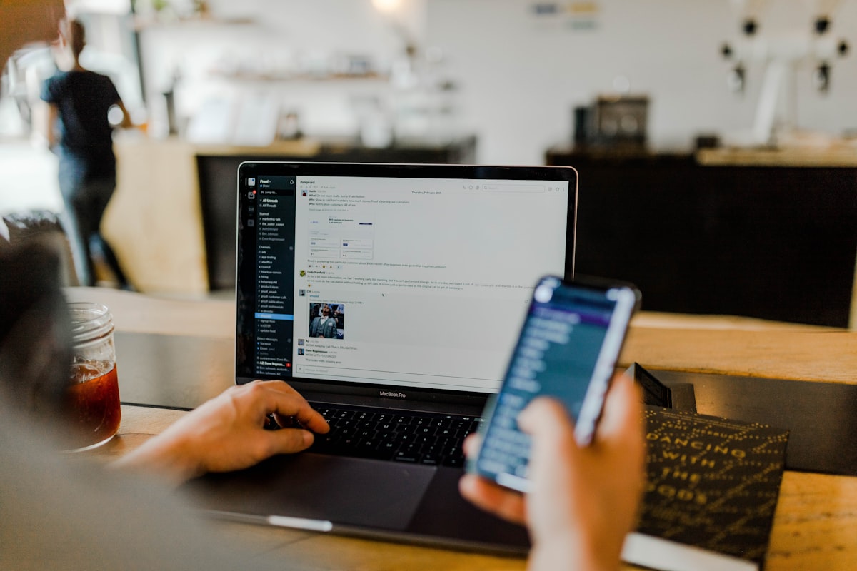 Person arbeitet mit Laptop und Smartphone an Social-Media-Inhalten